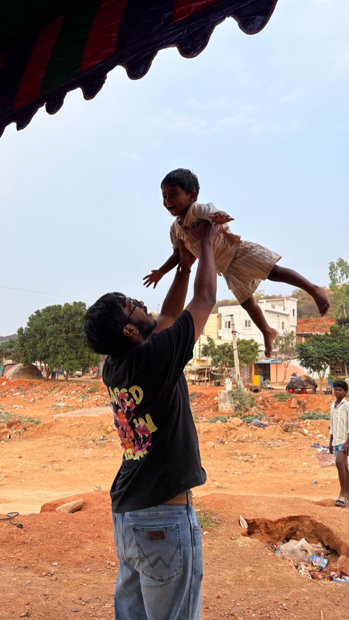 A Street Cause VNR volunteer lifting a laughing child into the air outdoors