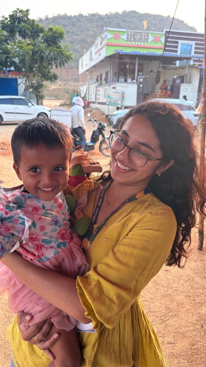 A Street Cause VNR volunteer crouching to talk with a child at a camp